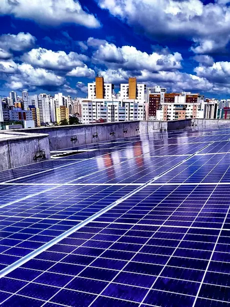Modulos fotovoltaicos em laje de edificio, com o horizonte urbano ao fundo